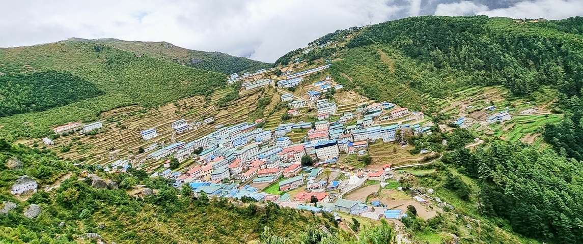       Hillside town with many buildings surrounded by green hills.
  