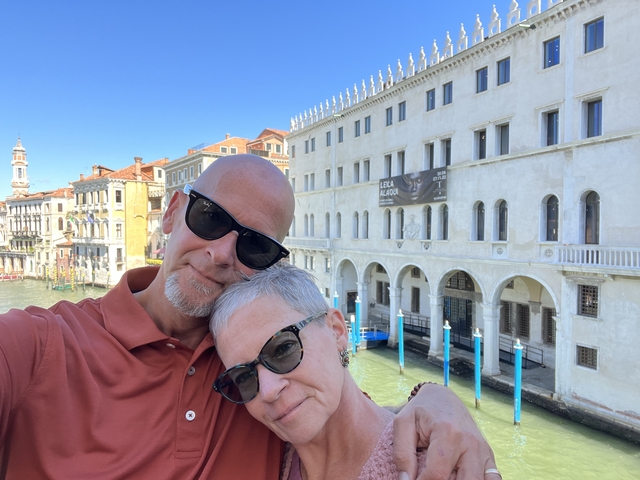 Couple taking a selfie with Venetian architecture in the background.