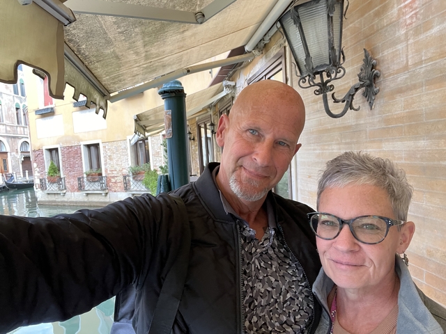 Two people taking a selfie in a quaint canal setting.