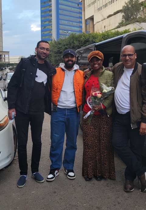 Group of people posing with flowers on a sidewalk.