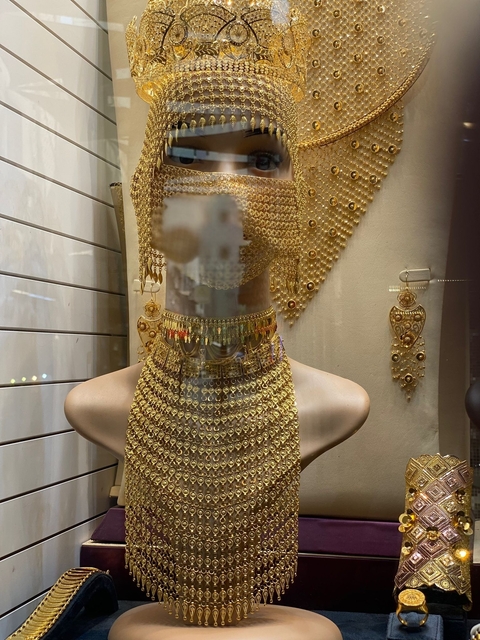Gold jewelry display in a shop window with intricate designs.