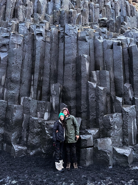 Two people standing in front of basalt columns.
