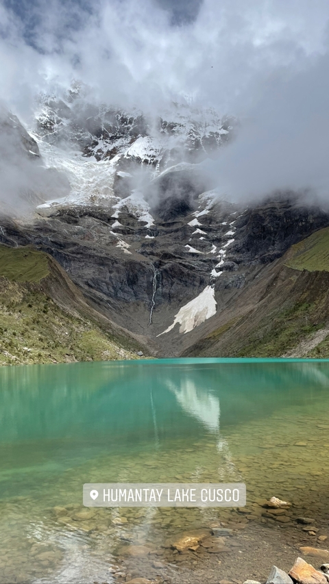 Turquoise lake surrounded by mountains with snow patches.