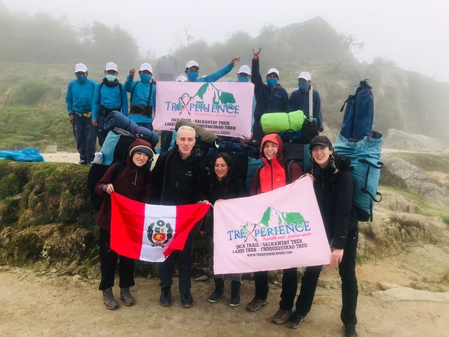       Group of trekkers posing with flags on a mountain trek.
  