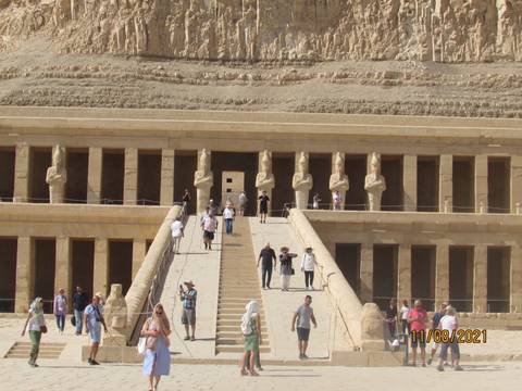 Hatshepsut Temple with tourists walking up and down stairs.