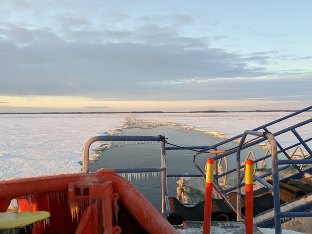 Frozen sea landscape with a breaking ice path, an orange life ring, and a railing.