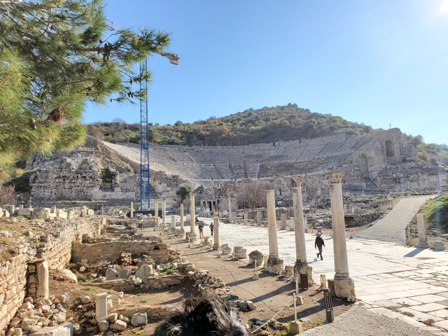       Historical amphitheater with pillars and a person walking nearby.
  