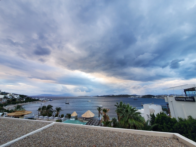       Cloudy skies over a coastal town with boats and hotels by the water.
  