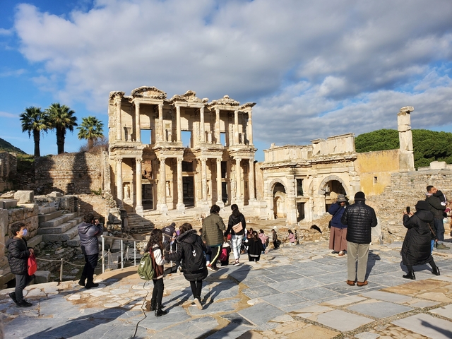       Tourists exploring much-visited ancient ruins with iconic columned buildings.
  