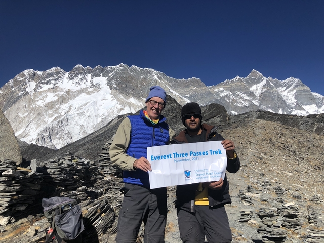 Two people holding a trekking sign in the mountains.