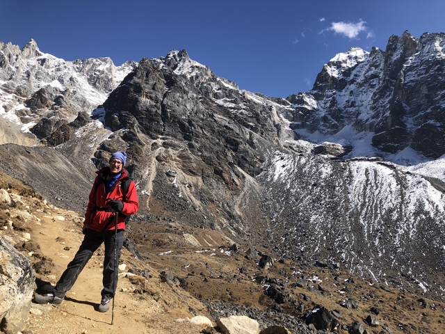 Person hiking near rocky snowy mountains.
