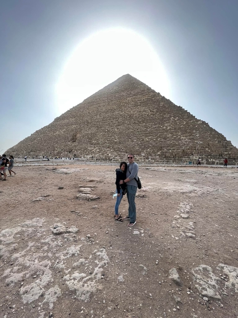       Two people standing in front of a pyramid.
  
