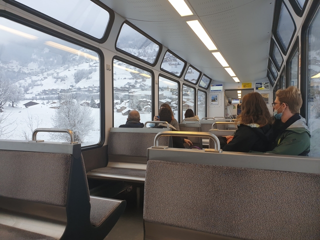       People on a train with scenic snow views.
  
