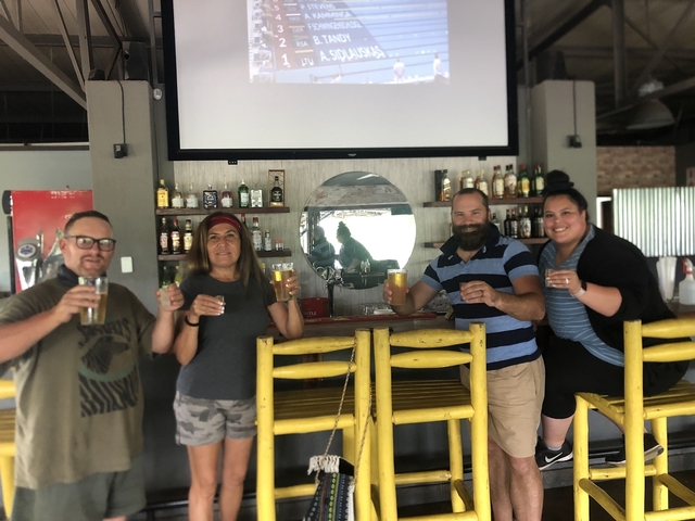Group of people holding drinks at a bar.