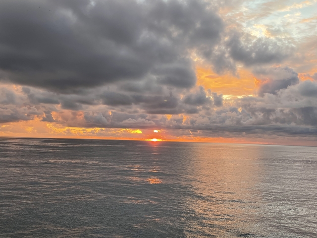       Dramatic sunset over the ocean with clouds reflecting on the water.
  