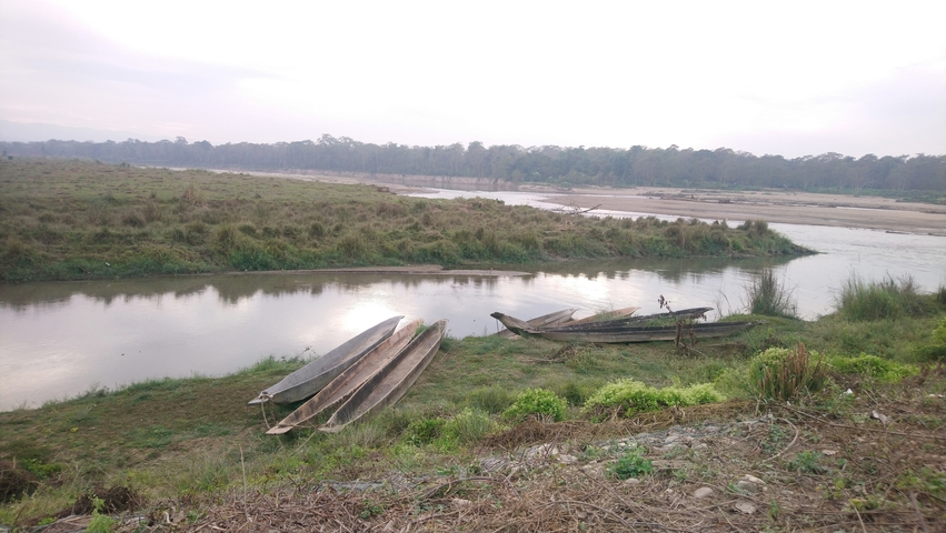       River landscape with narrow wooden boats on the shore.
  
