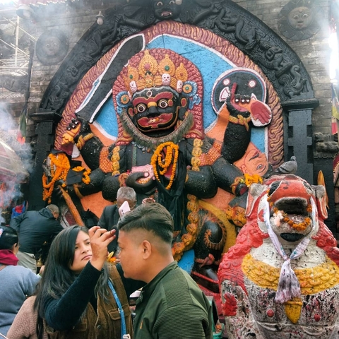       Large decorative statue with people taking photos and offering prayers.
  
