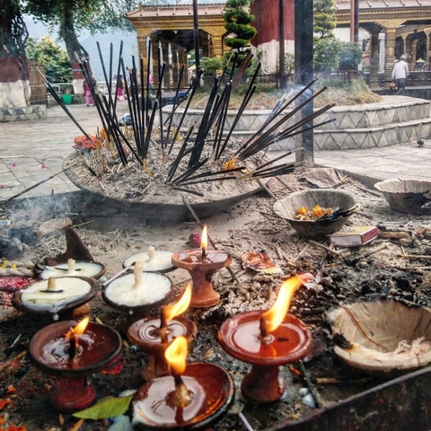       Burning incense and candles at an outdoor shrine.
  
