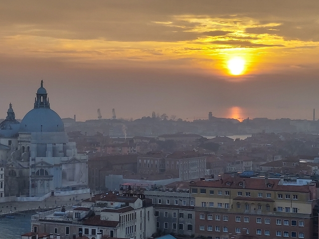 Cityscape under a vibrant sunset with a prominent dome