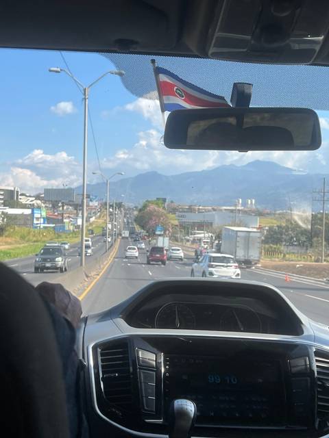       View from inside a vehicle showing a busy road and mountains.
  