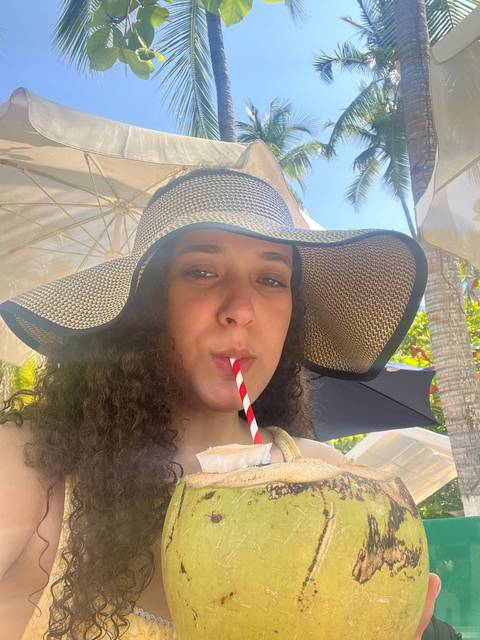 Person drinking coconut water under palm trees.