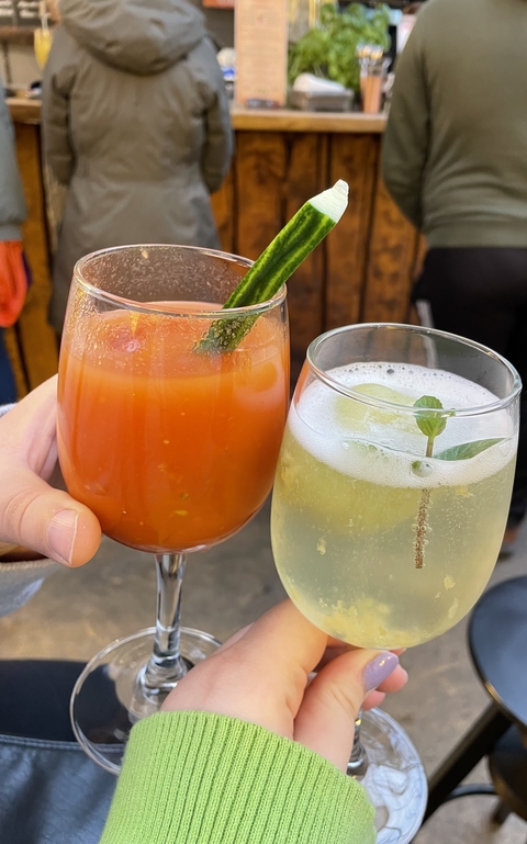 Two drinks in glasses, one with a red beverage and the other with a green-colored drink.
