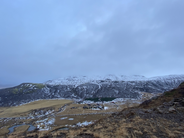 Snow-covered mountainous landscape under a cloudy sky.