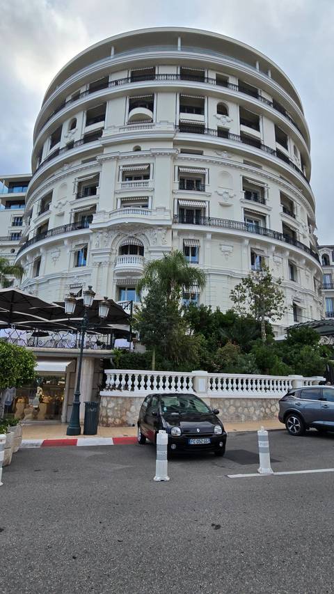A grand historic building with vehicles parked in front.