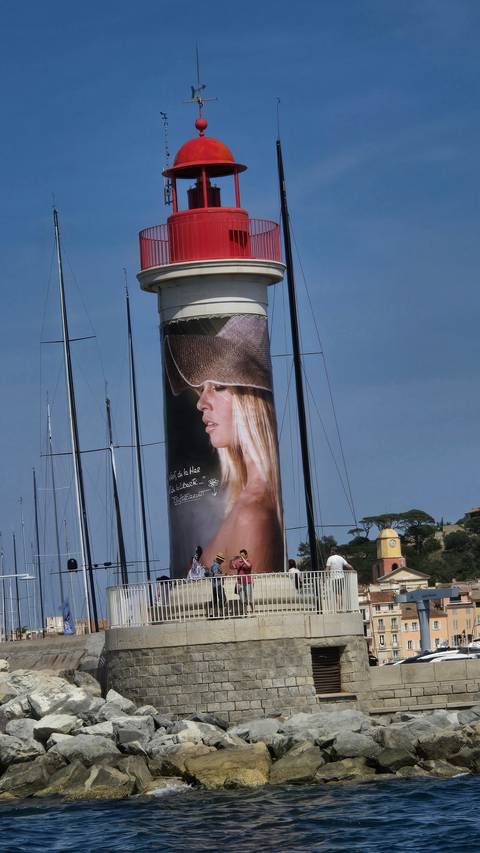 A lighthouse with large promotional mural beside a marina.