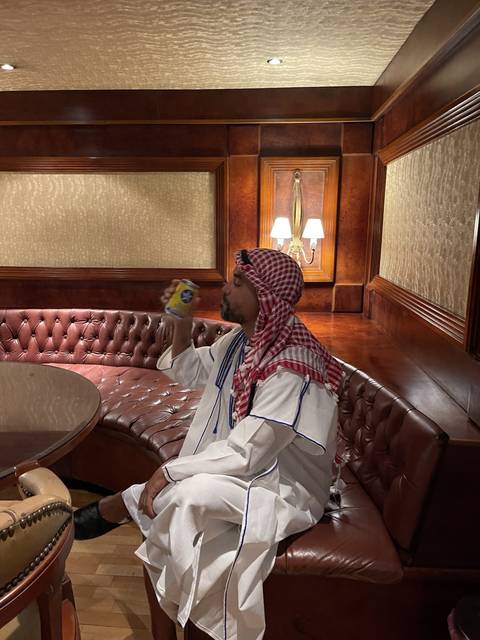 Person indoors relaxing on a couch in traditional clothing.