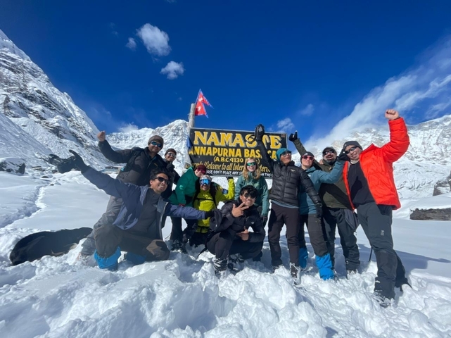 Group of hikers posing with a sign at Annapurna Base Camp.