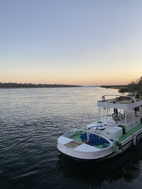       A boat on a river at sunset.
  