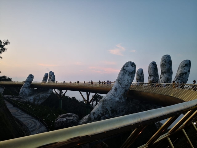       The Golden Bridge with giant stone hands at sunset.
  
