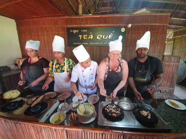       A group of people wearing chef hats cooking together.
  