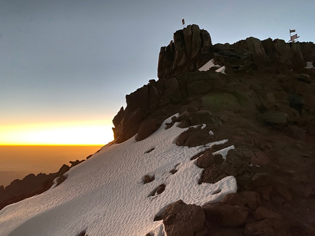 Sunset over snowy mountainous terrain.