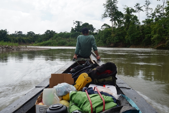 Person sitting on a boat with luggage on a river.
