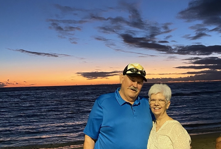 Couple standing by the ocean at sunset.