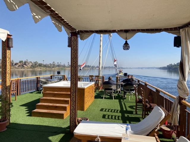 View from a riverboat with a deck and distant sailboats.