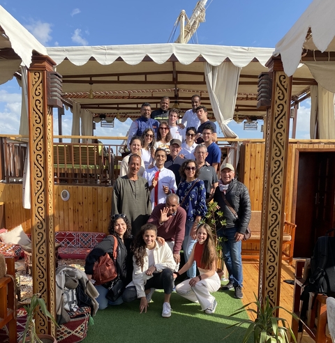 A group of people posing on a wooden deck of a boat.