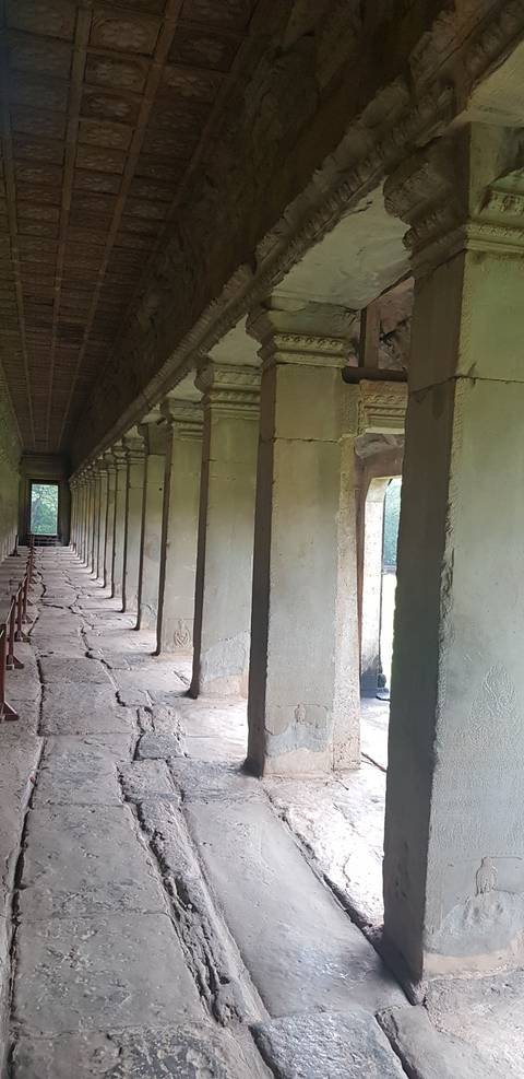 Long corridor with stone pillars in an ancient site.