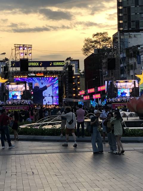 Outdoor concert stage with crowd during sunset.