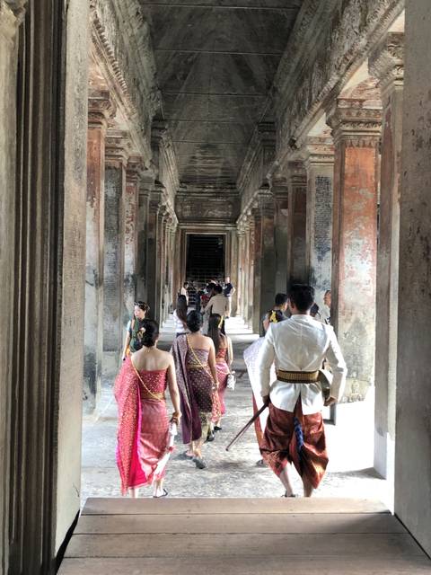       People dressed in traditional attire walking through a temple.
  