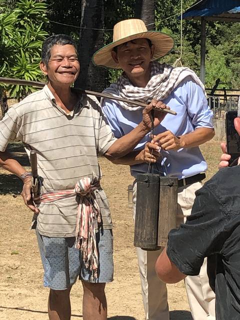       Two men posing with traditional instruments.
  