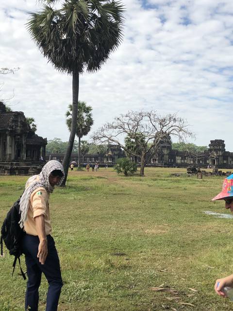 Person walking on grass with Angkor Wat in the background.