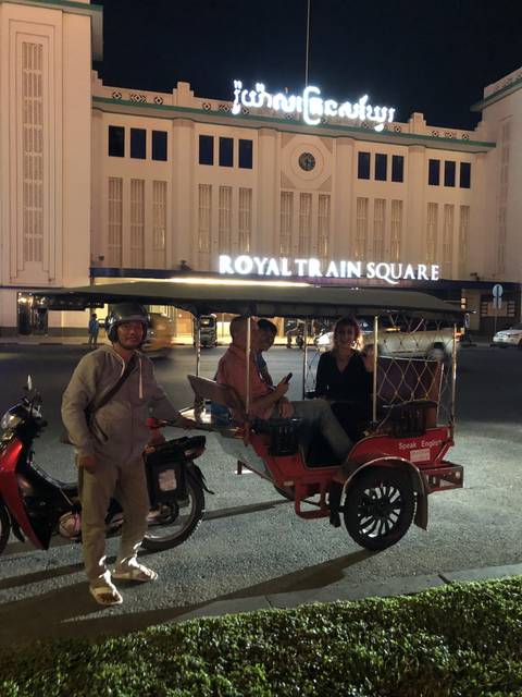       Group riding a colorful vehicle at night outside a train station.
  