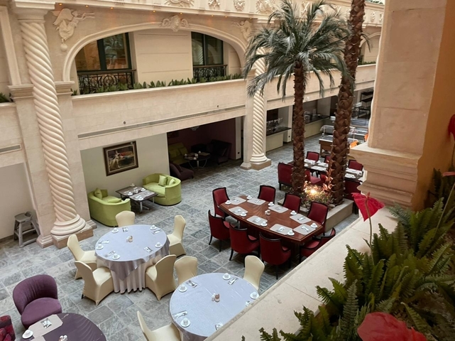 Hotel atrium with dining tables and trees.