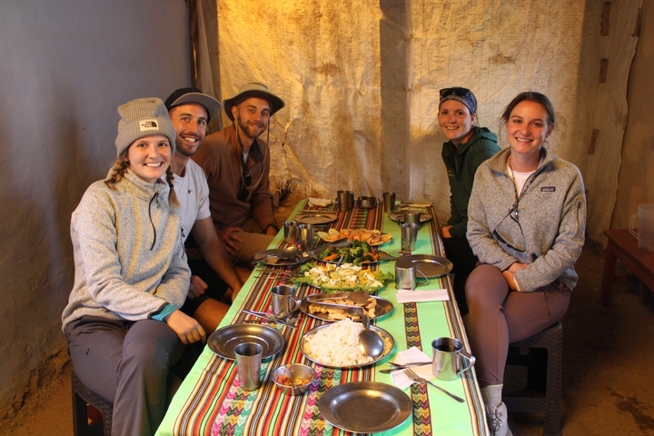 Five people sitting at a table with local food.