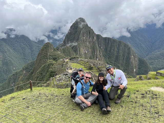 Family posing at Machu Picchu with the mountain in the background.