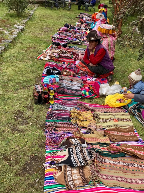       Colorful traditional weavings and goods displayed on the ground.
  