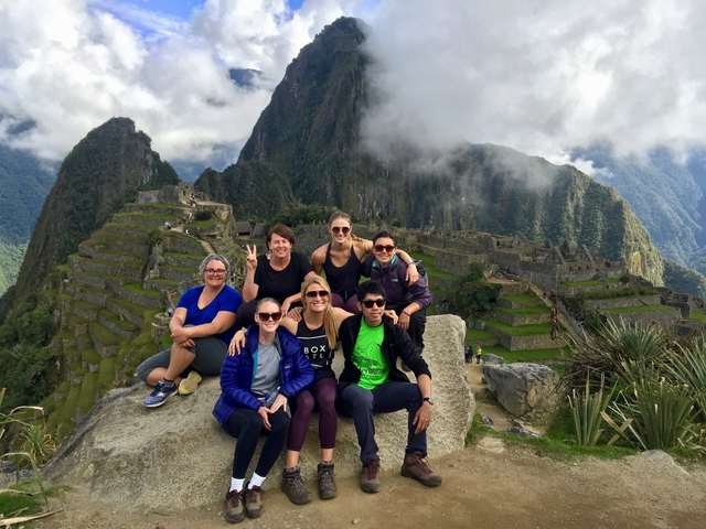       Tour group posing on a rock with Machu Picchu in the background.
  